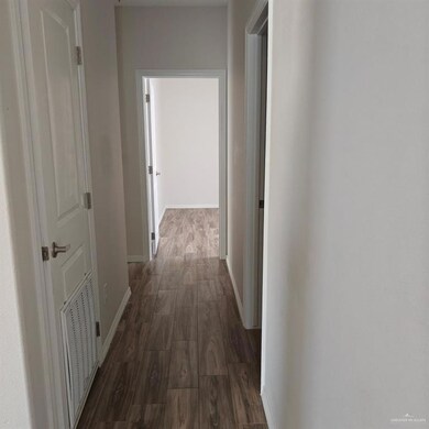 Hallway featuring dark wood-style flooring, baseboards, and visible vents