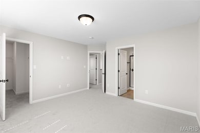 Unfurnished bedroom with ensuite bath, a spacious closet, a closet, and light colored carpet