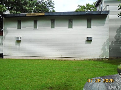 View of side of property with a yard and a wall unit AC