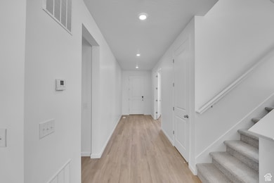 Hall with light wood-type flooring, recessed lighting, baseboards, and stairway