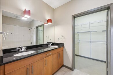 Bathroom featuring tile patterned flooring, double vanity, a shower, a walk in closet, and baseboards