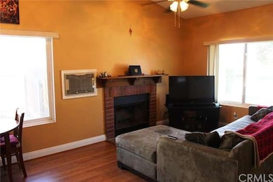 Living room with a cozy fireplace, ceiling fan, an