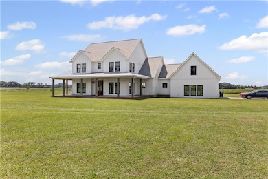 Modern farmhouse with covered porch, board and batten siding, a standing seam roof, and a front lawn