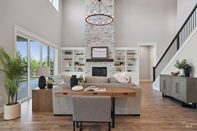 Living area with a towering ceiling, healthy amount of natural light, a chandelier, stairway, and wood finished floors