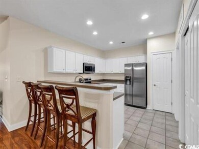 Kitchen featuring white cabinets, a peninsula, a b