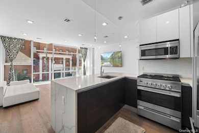 Kitchen featuring stainless steel appliances, modern cabinets, a peninsula, light stone countertops, and recessed lighting
