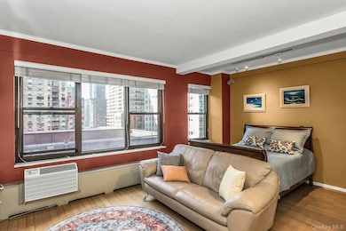 Bedroom with track lighting, wood-type flooring, a wall mounted AC, a baseboard heating unit, and beam ceiling