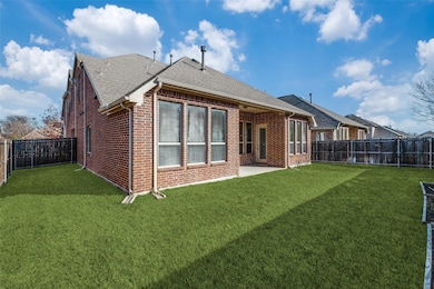 Back of property with brick siding, a patio area, a fenced backyard, and a shingled roof