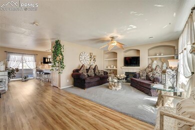 Living area featuring built in shelves, a tiled fireplace, a ceiling fan, a textured ceiling, and wood finished floors