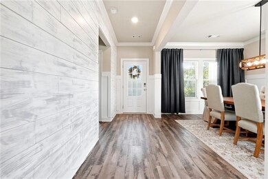 Entrance foyer featuring dark wood-type flooring, wainscoting, ornamental molding, and a decorative wall