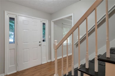 Foyer entrance featuring wood finished floors, stairway, plenty of natural light, and a textured ceiling