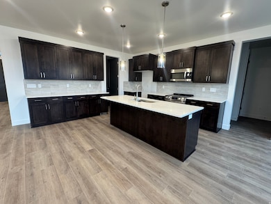 Kitchen featuring tasteful backsplash, dark brown cabinets, appliances with stainless steel finishes, pendant lighting, and recessed lighting