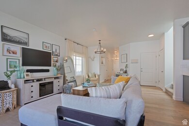 Living area with light wood-style floors, a chandelier, and recessed lighting