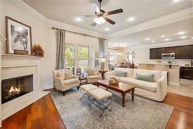 The open concept living area has wood floors, high ceilings and a wall of windows overlooking the patio and fenced yard. The gas fireplace and crown Moulding complete the space.