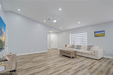 Living room featuring vaulted ceiling, light wood-