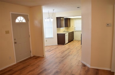 Foyer with light wood-type flooring and a chandel