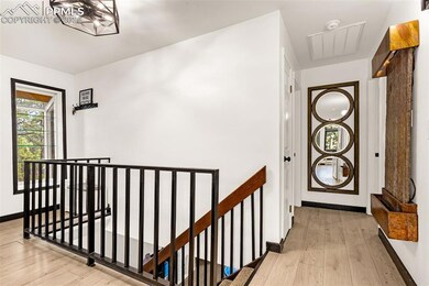 Corridor with baseboards, visible vents, wood finished floors, and an upstairs landing