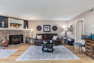 Living area with a textured ceiling, wood finished floors, a brick fireplace, and recessed lighting