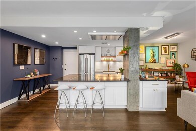 Kitchen with freestanding refrigerator, dark countertops, a peninsula, dark wood finished floors, and recessed lighting