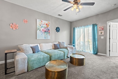 Living room featuring carpet, a textured ceiling, and a ceiling fan