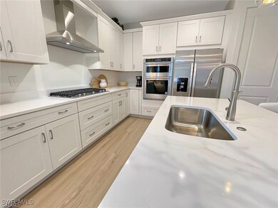 Kitchen featuring wall chimney exhaust hood, appli