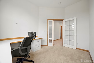 Looking from the office toward the tile hallway with the laundry room and garage entry beyond.