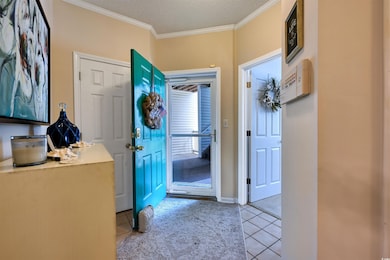 Entrance foyer featuring light tile patterned floors, crown molding, and a textured ceiling