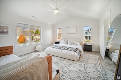 Bedroom with lofted ceiling, a ceiling fan, and carpet floors