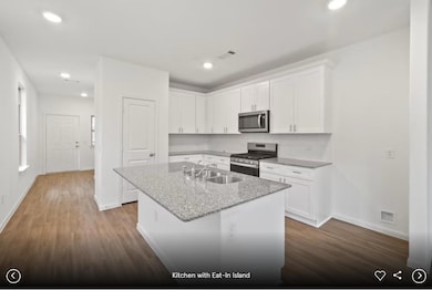 Kitchen featuring light stone counters, white cab