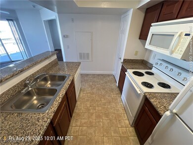 Kitchen with white appliances, dark brown cabinets, and dark stone countertops