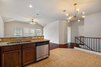 Kitchen with dishwasher, lofted ceiling, open floor plan, light tile patterned floors, and light stone counters