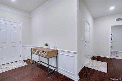 Foyer featuring dark wood finished floors and crown molding