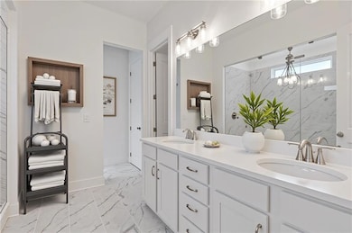 Full bathroom featuring double vanity, a marble finish shower, and light marble finish floors