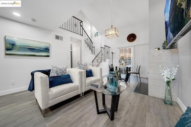 Living area with a towering ceiling, stairway, light wood-style floors, and a chandelier