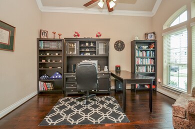 Study with hardwood floors, crown molding and high