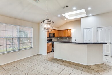 Kitchen with a skylight, backsplash, black appliances, vaulted ceiling, and a chandelier