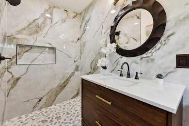 Bathroom with tile walls, vanity, and a tile show