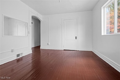 Spare room with dark wood finished floors and arched walkways