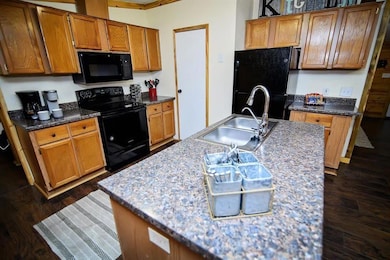 Kitchen with black appliances, a sink, dark wood f