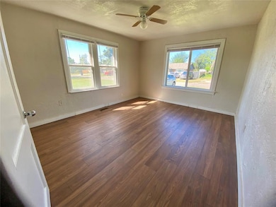 Spare room with a textured wall, healthy amount of natural light, wood finished floors, a textured ceiling, and ceiling fan