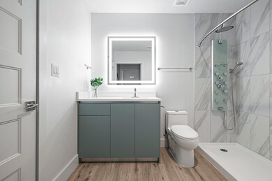 Full bath featuring toilet, tiled shower, wood fi