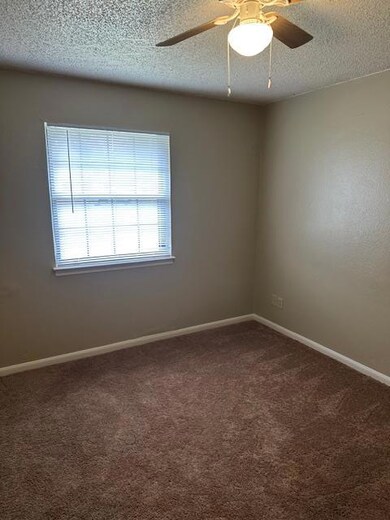 Carpeted spare room with baseboards, a ceiling fa