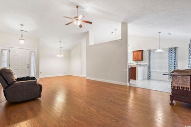 Living room featuring a ceiling fan, light wood-style flooring, a textured ceiling, and high vaulted ceiling