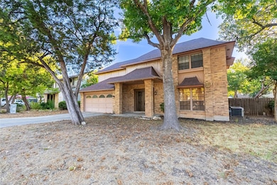 View of front facade with a shingled roof, brick siding, driveway, and an attached garage