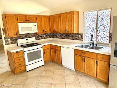 Kitchen with white appliances, a sink, backsplash,