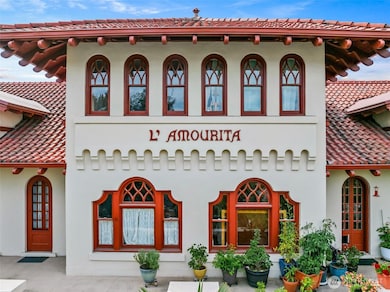Charming arches and red-tiled eaves, a warm and timeless welcome to historic L’Amourita—Seattle’s cherished 1909 treasure.