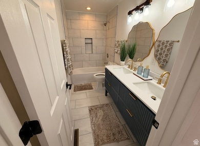 Bathroom featuring double vanity, shower / bathtub combination, and tile patterned flooring