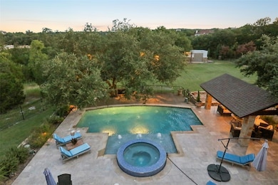 Pool at dusk with a fenced backyard, a patio area