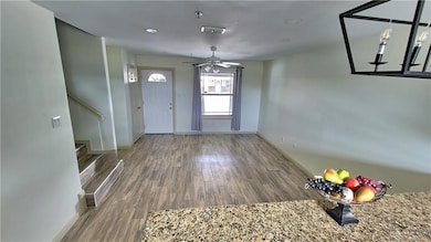 Foyer with wood finished floors, ceiling fan, and stairway