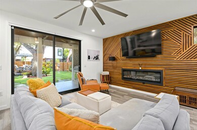 Living area with an accent wall, ceiling fan, rec